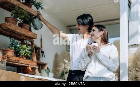 Liebhaber verbringen ihre Zeit damit, auf den stilvollen Balkonen auf dem Dach kleine Gärten, Pflanzen und frische Blumen zu bewässern. Entspannen Sie sich in ordentlichem Raum. Mit der Natur zurechtkommen Stockfoto