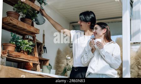 Liebhaber verbringen ihre Zeit damit, auf den stilvollen Balkonen auf dem Dach kleine Gärten, Pflanzen und frische Blumen zu bewässern. Entspannen Sie sich in ordentlichem Raum. Mit der Natur zurechtkommen Stockfoto