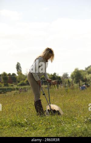 Eine blonde Frau, die auf einem Pferdefeld kackte Stockfoto