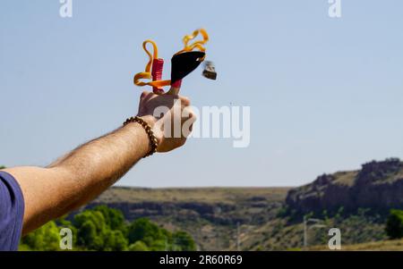 Ein Mann mit Speerwerfer, der Naturunterhaltung mit Steinen wirft Stockfoto