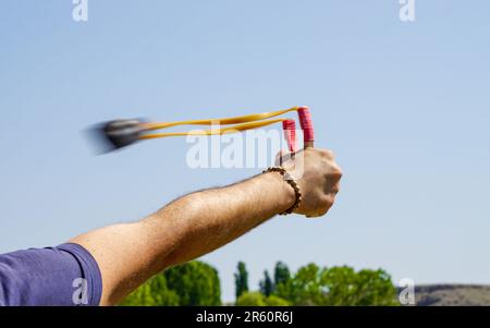 Ein Mann mit Speerwerfer, der Naturunterhaltung mit Steinen wirft Stockfoto