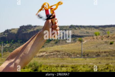 Ein Mann mit Speerwerfer, der Naturunterhaltung mit Steinen wirft Stockfoto