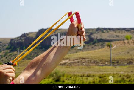 Ein Mann mit Speerwerfer, der Naturunterhaltung mit Steinen wirft Stockfoto