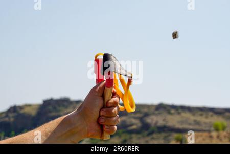 Ein Mann mit Speerwerfer, der Naturunterhaltung mit Steinen wirft Stockfoto