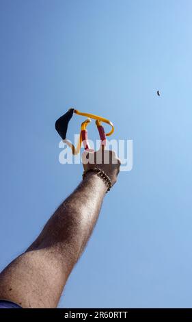 Ein Mann mit Speerwerfer, der Naturunterhaltung mit Steinen wirft Stockfoto