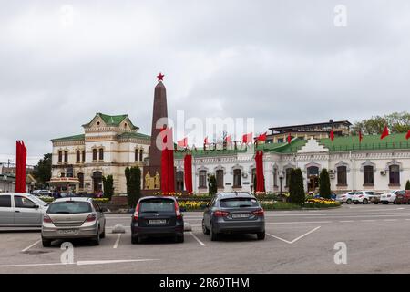 Essentuki, Russland - 9. Mai 2023: Straßenblick mit Autos, die vor dem Hauptbahnhof am Bahnhofsplatz geparkt sind, dekoriert mit roten Flaggen zu Ehren des D. Stockfoto