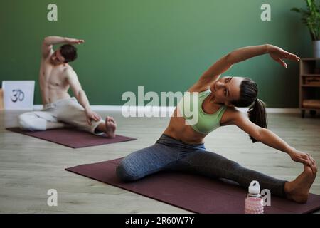 Porträt einer fit-jungen Frau, die im Yoga-Kurs drinnen Stretches macht, Kopierraum Stockfoto