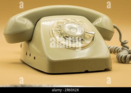 Ein altmodisches 70s-Telefon mit dunkelpastellfarbenem orangefarbenen Hintergrund Stockfoto