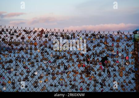 Nahaufnahme eines weißen Lattenzauns mit mehreren Schlössern und Schlüsseln in verschiedenen Formen und Größen Stockfoto