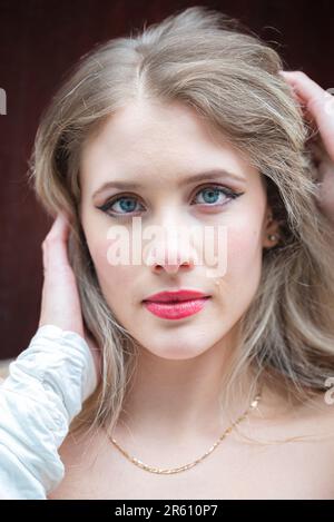 Eine junge blonde weiße Frau, die in einem weißen Top posiert Stockfoto