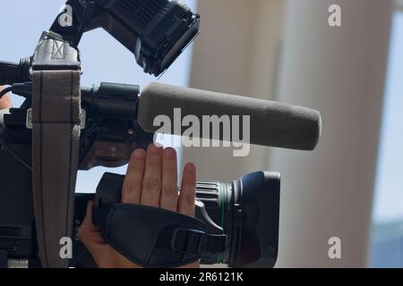 Bild eines Kamerabetreibers, der einen Fernsehbericht während einer Nachrichtenveranstaltung aufzeichnet Stockfoto