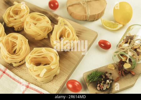 Rohe und frische hausgemachte Pasta auf dem Tisch, Nahaufnahme. Kochkonzept. Seitenansicht auf dunklem Hintergrund. Speicherplatz kopieren Stockfoto