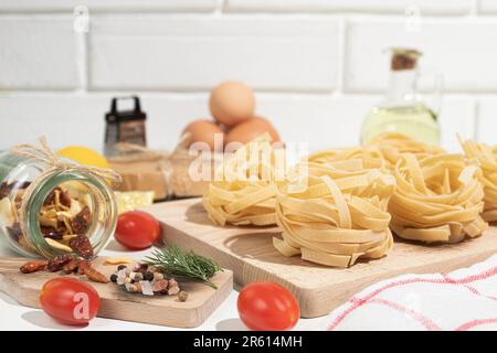 Rohe und frische hausgemachte Pasta auf dem Tisch, Nahaufnahme. Kochkonzept. Seitenansicht auf dunklem Hintergrund. Speicherplatz kopieren Stockfoto