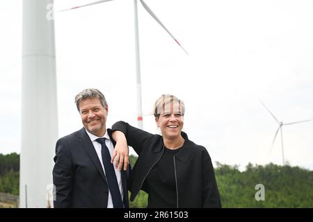 06. Juni 2023, Nordrhein-Westfalen, Bad Berleburg: Robert Habeck (l), Bundeswirtschaftsminister und Wirtschaftsministerin Mona Neubaur (beide Grüne), scherzen vor Windkraftanlagen, um Strom zu erzeugen. Die Wittgenstein-Gruppe und der NRW State Association for Renewable Energies beauftragen offiziell den Waldwindpark Arfeld mit vier Windturbinen, der seit Herbst 2022 in Betrieb ist. Foto: Federico Gambarini/dpa Stockfoto