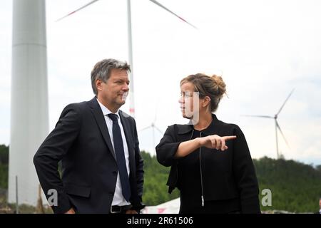 06. Juni 2023, Nordrhein-Westfalen, Bad Berleburg: Robert Habeck (l), Bundesminister für Wirtschaft, und die Wirtschaftsministerin Mona Neubaur (beide Grüne) des NRW stehen zur Stromerzeugung vor Windturbinen. Die Wittgenstein-Gruppe und der NRW State Association for Renewable Energies beauftragen offiziell den Waldwindpark Arfeld mit vier Windturbinen, der seit Herbst 2022 in Betrieb ist. Foto: Federico Gambarini/dpa Stockfoto