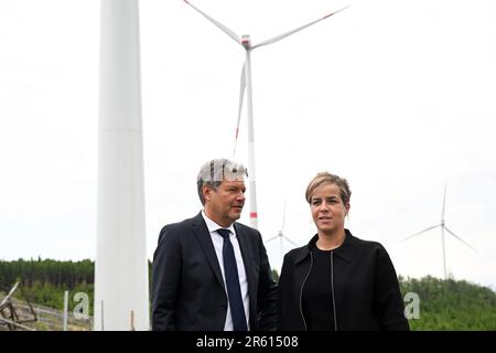 06. Juni 2023, Nordrhein-Westfalen, Bad Berleburg: Robert Habeck (l), Bundesminister für Wirtschaft, und die Wirtschaftsministerin Mona Neubaur (beide Grüne) des NRW stehen zur Stromerzeugung vor Windturbinen. Die Wittgenstein-Gruppe und der NRW State Association for Renewable Energies beauftragen offiziell den Waldwindpark Arfeld mit vier Windturbinen, der seit Herbst 2022 in Betrieb ist. Foto: Federico Gambarini/dpa Stockfoto