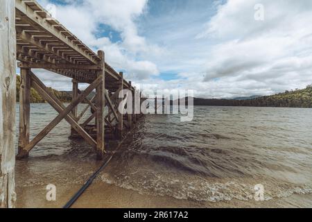 Ein hölzerner Pier, der sich über ein ruhiges Gewässer erstreckt Stockfoto