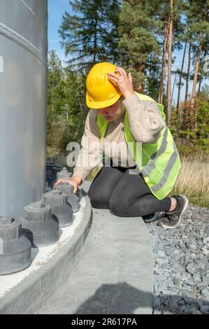 Eine Ingenieurin mit gelbem Schutzhelm, die auf Rohre schaut Stockfoto