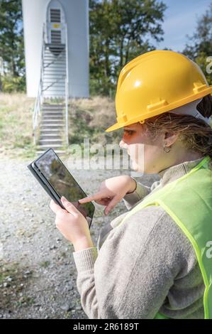 Eine Ingenieurin mit gelbem Schutzhelm zeigt auf ihr Tablet Stockfoto