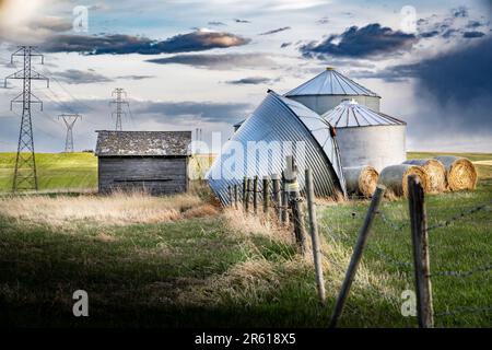 Grain Silos wurde nach einem heftigen Gewitter zusammengeklappt und überblickte die Übertragungstürme und Felder mit Stacheldrahtzaun in Rockyview County Stockfoto