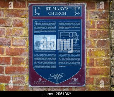 Surrey, Großbritannien - April 5. 2023: Eine Plakette an der Fassade von St. Die Marys Church in Guildford, Surrey, erläutert die Geschichte des Gebäudes. Stockfoto