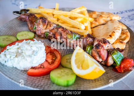 Griechisches Schweinefleisch Souvlaki mit Tzatziki-Sauce und frischem Gemüse, gegrillte Kebabs Stockfoto