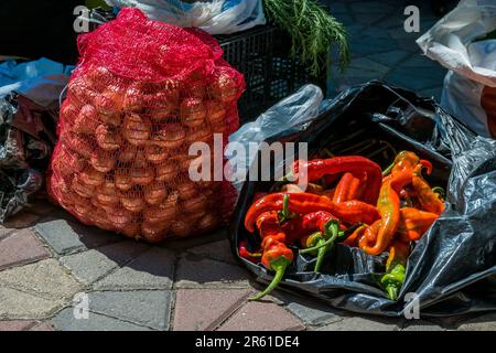 Ein Straßenverkäufer, der Obst und Gemüse wie Chilis und Zwiebeln auf einem Gehweg in der Nähe eines grünen, offenen Marktes in der Stadt Tetovo, Nordmazedonien, verkauft. Stockfoto