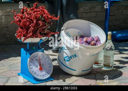 Ein Straßenverkäufer, der Obst und Gemüse wie Chilis und Pflaumen auf einem Gehweg in der Nähe eines grünen, offenen Marktes in der Stadt Tetovo, Nordmazedonien, verkauft. Stockfoto