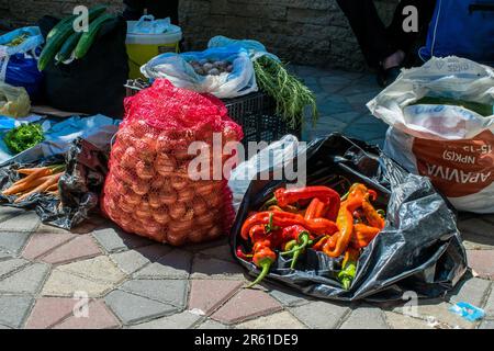 Ein Straßenverkäufer, der Obst und Gemüse wie Chilis und Zwiebeln auf einem Gehweg in der Nähe eines grünen, offenen Marktes in der Stadt Tetovo, Nordmazedonien, verkauft. Stockfoto