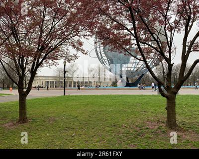 Kirschblüten umrahmen die Unisphere, eine Edelstahlkugel im Flushing Meadows Corona Park, Heimstadion der New York Worlds Fair Stockfoto