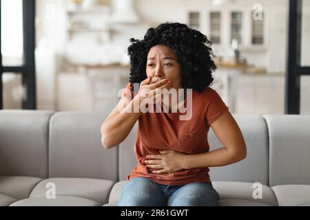 Junge Schwarze, Die An Übelkeit Leidet, Während Sie Zu Hause Auf Der Couch Sitzt Stockfoto