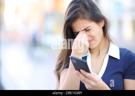 Gestresste Frau, die ein Telefon auf der Straße hält Stockfoto