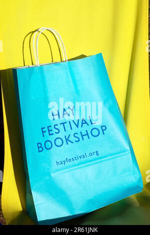 Türkisblaue Tragetasche für den Hay Festival Bookshop auf gelbem Segeltuchboden beim Hay Festival 2023 in Hay-on-Wye Wales UK Stockfoto