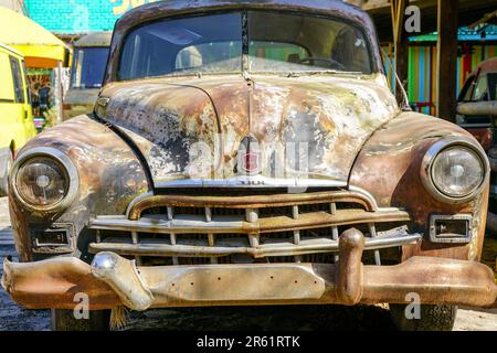 Verlassenes rostiges historisches Autowrack aus den 1950er Jahren, Blick nach vorne, sowjetisches Auto GAZ-12 ZIM als Café-Dekor im Freien Stockfoto