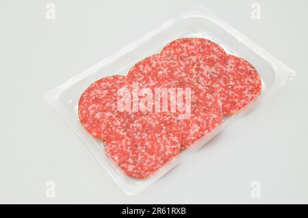 Salami-Scheiben in einer Plastikbox, isoliert auf weißem Hintergrund Stockfoto
