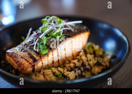 Ein köstlicher Teller mit gegrilltem Lachsbauch, serviert über einem Bett aus herzhaften Gerstenkörnern Stockfoto