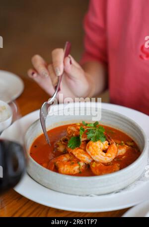 Ein Teller mit verschiedenen Meeresfrüchtespezialitäten, serviert mit einer Schüssel dampfender Tomatensuppe Stockfoto