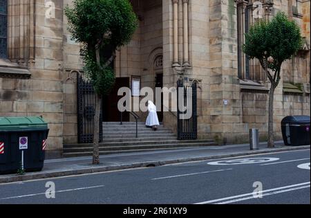 Bilbao, Spanien - 03. August 2022: Eine Nonne mit weißer Angewohnheit steigt die Treppe der Kirche San Francisco de Asís, auch bekannt als La Quinta Par Stockfoto