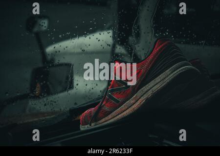 Der leuchtend pinkfarbene Schuh liegt auf dem Armaturenbrett eines 18-rädrigen Fahrzeugs vor einem regnerischen Truckstop-Hintergrund. Ein Farbakzent in der Welt der Fernfahrer. #ColorContrast # Stockfoto