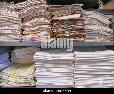 Ein Stapel gefalteter sauberer Laken oder Stoffe in einer industriellen Wäscherei. Dienstleistungen für Hotels, Krankenhäuser, Kliniken und Unternehmen Stockfoto