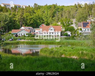 Bäume und Häuser auf dem Feld am See gegen den Himmel Stockfoto