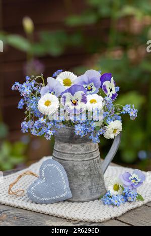 Ein Strauß violetter Violettblüten, bellis und vergiss mich, keine Blumen im alten Krug Stockfoto