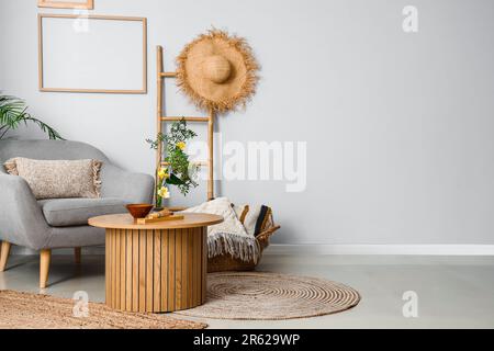 Wohnzimmereinrichtung mit Ikebana auf Tisch und Sessel Stockfoto