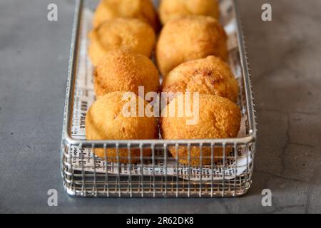 Ein Metallkorb gefüllt mit frisch zubereitetem, herzhaftem Gebäck mit knuspriger, goldbrauner Panade Stockfoto