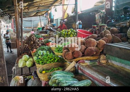 Toliara, Madagaskar - 01. Mai 2019: Typischer madagassischer Straßenmarkt - einheimisches Gemüse in einfachen Hütten, braune Baobab-Früchte im Vordergrund Stockfoto