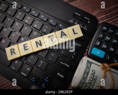 Eine Tastatur und Holzblöcke mit dem Wort Vermietung auf Holzhintergrund Stockfoto