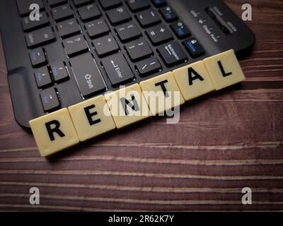 Eine Tastatur und Holzblöcke mit dem Wort Vermietung auf Holzhintergrund Stockfoto