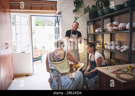 Wo Töpfer spielen. Eine Gruppe junger Leute, die mit Ton in einem Töpferstudio arbeiten. Stockfoto