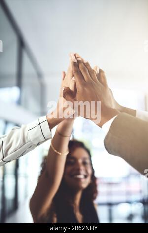 All unsere Bemühungen haben uns einen weiteren Sieg beschert. Nahaufnahme einer Gruppe von Geschäftsleuten, die sich in einem Büro gegenseitig einen High Five geben. Stockfoto