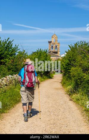 Pilger auf dem Camino nach Santiago de Compostela in Santa Catalina de Somoza, Castilla y Leon, Spanien, mit Iglesia Parroquial de Santa Maria Stockfoto